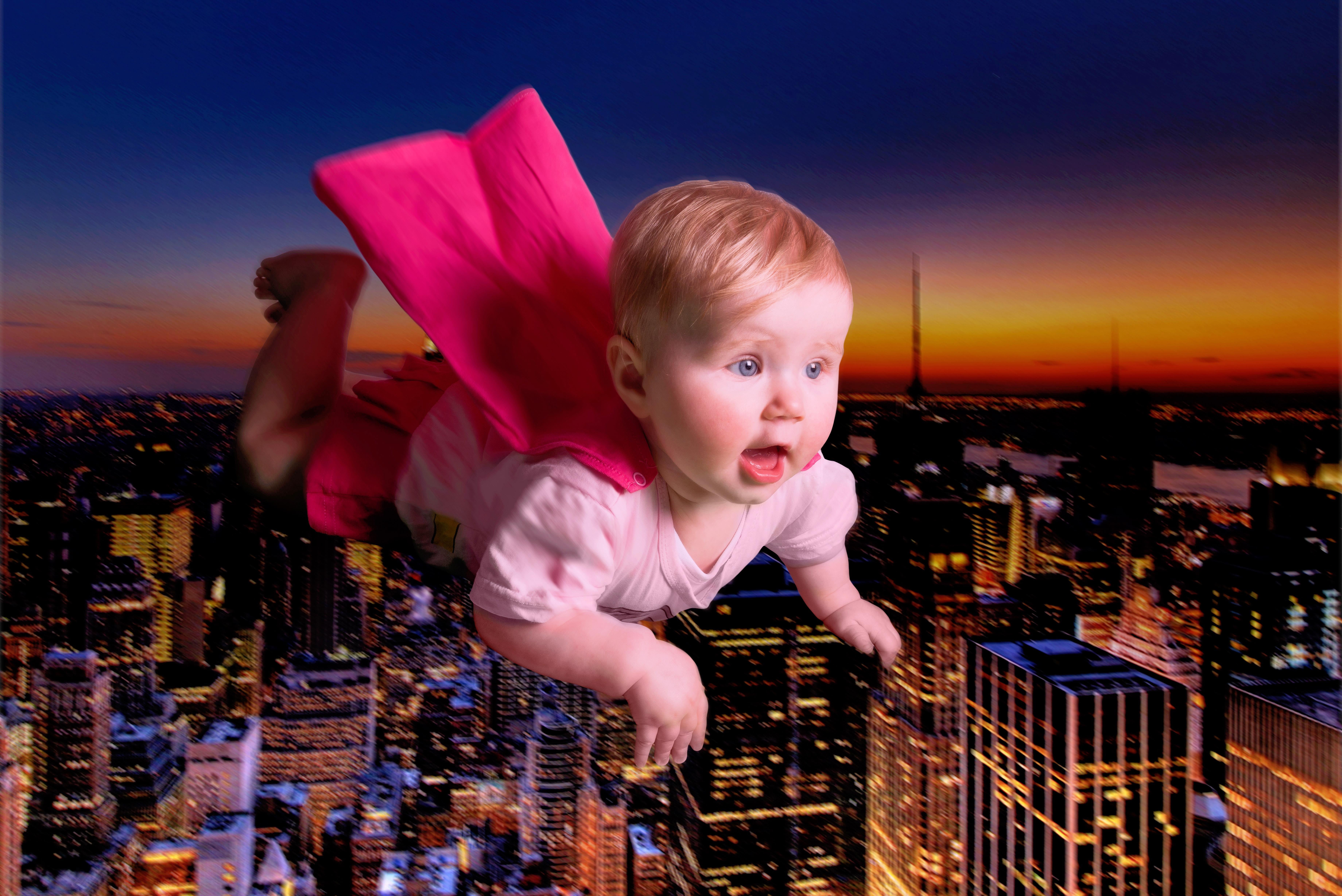 Billedmanipulation af en lille pige der i ført kappe flyver over en stirby